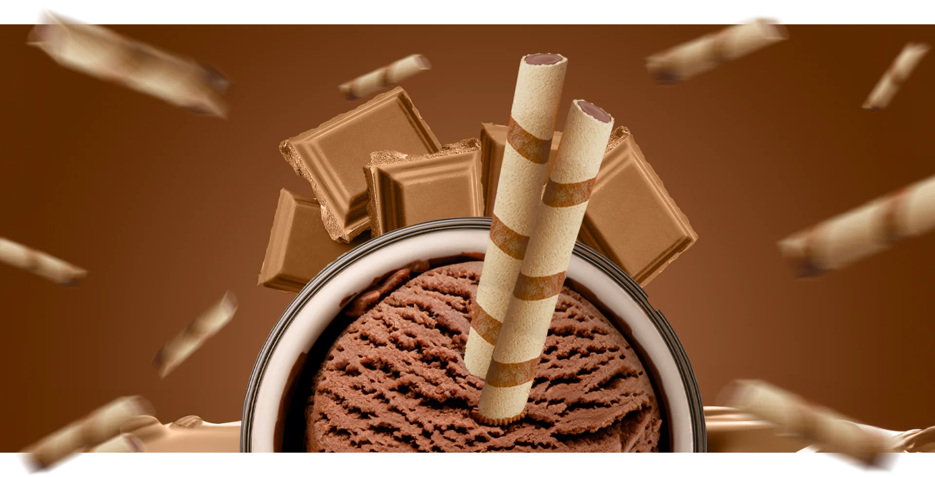 Bowl of rich chocolate ice cream topped with chocolate wafer roll sticks and surrounded by chunks of chocolate.